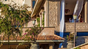 Un bâtiment doté d’un balcon, de colonnes en pierre et d’une toiture en tuiles de terre cuite.