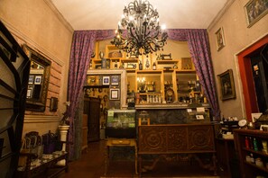 A vintage room with a chandelier, wooden furniture, and various decorative items. - Hotel Boutique Casa Isabella (Tepoztlán)