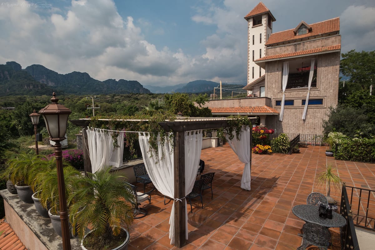 A patio with terracotta tiles, outdoor furniture, and potted plants.