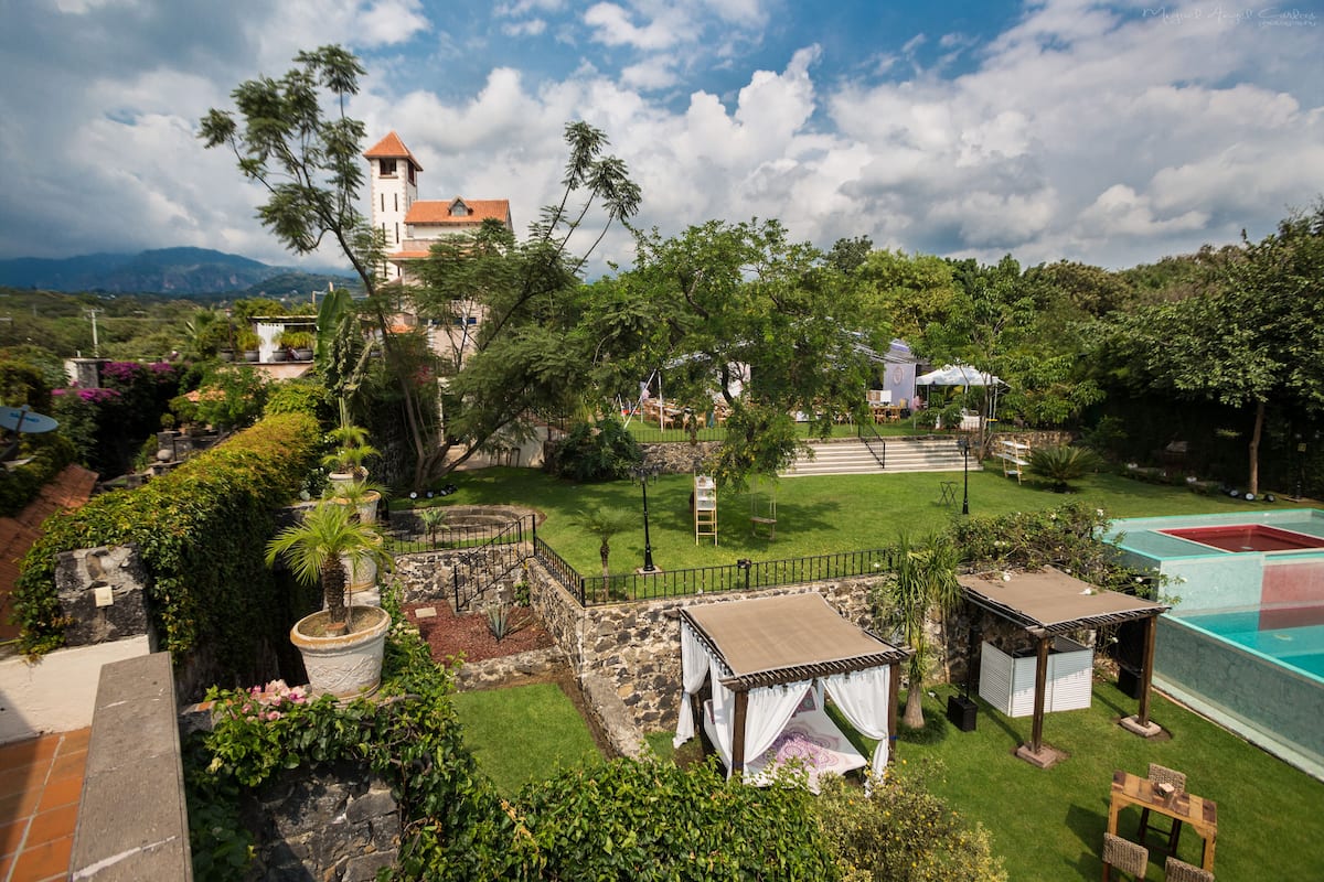 A lush garden with a gazebo, a pool, and a view of distant mountains.