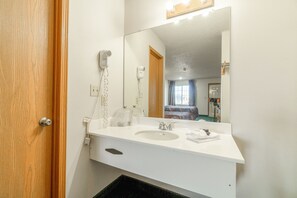 A bathroom with a white sink, a mirror, a hairdryer, and a towel.