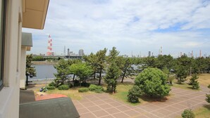 Une vue depuis une fenêtre donnant sur un parking, avec des arbres et une étendue d’eau en arrière-plan.