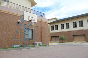 Una cancha de baloncesto al lado de un edificio de ladrillo y cerca de una valla metálica.