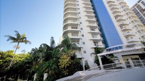 Un hotel alto con varios balcones y un llamativo elemento vertical azul.