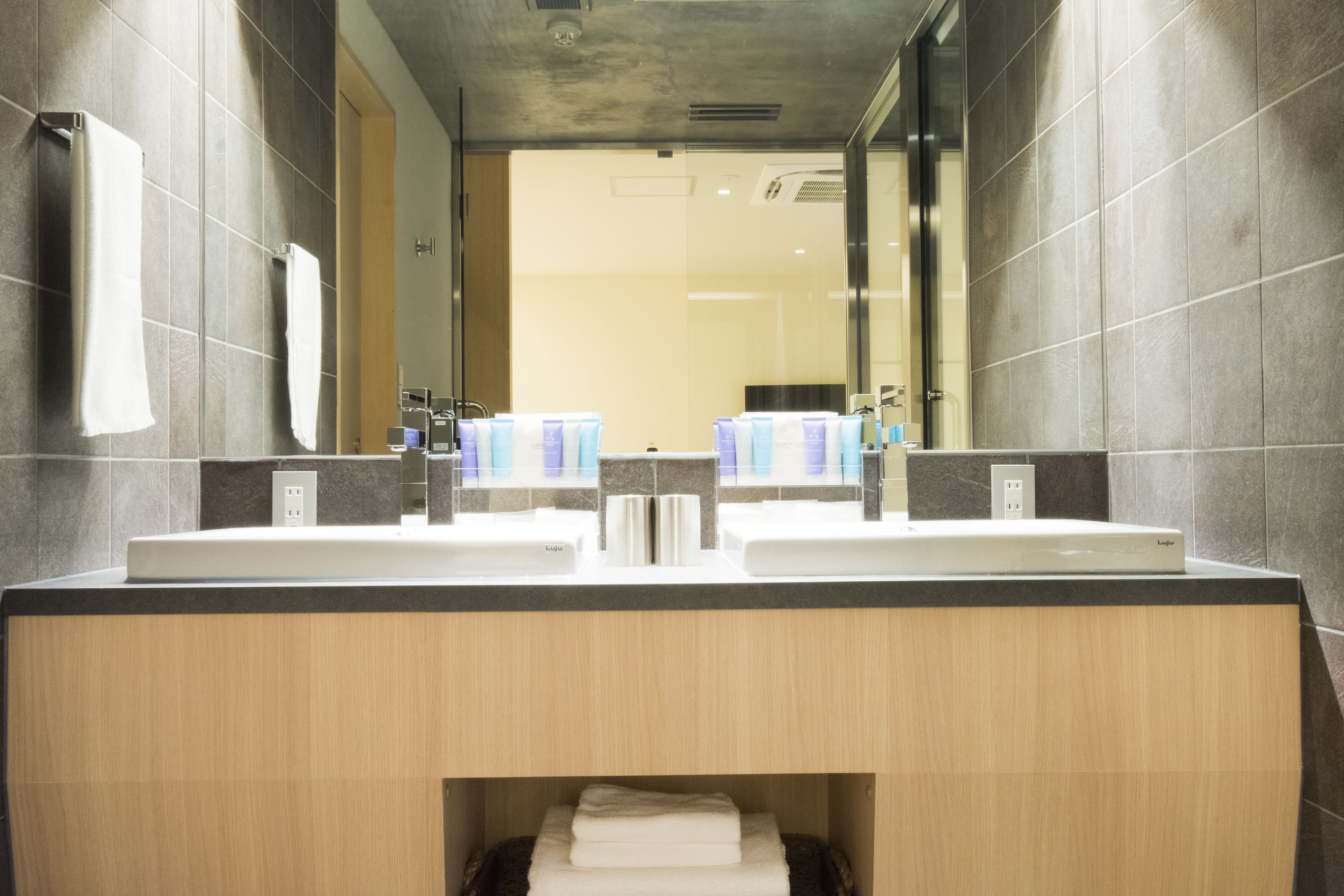 A modern bathroom with two sinks, a mirror, and a towel rack.