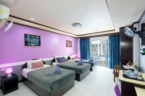 Habitación de hotel con dos camas, un balcón con cortinas azules y un comedor con mesa dispuesta para dos.