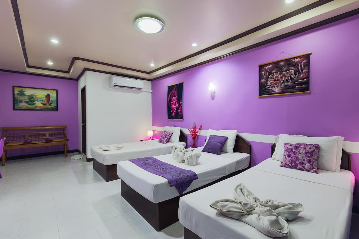 A hotel room with two beds, purple walls, and artwork.