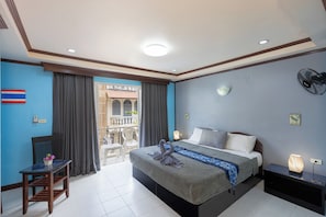 Una habitación de hotel con cama, escritorio, silla, balcón con vistas y una bandera en la pared.