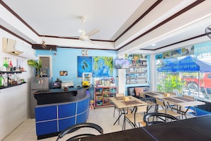 Un restaurante con mostrador azul, zona de estar y pared decorada con mapas y fotografías.