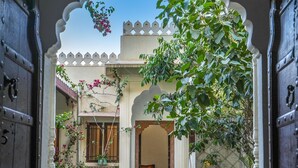 An entrance with a decorative archway, potted plants, and a view into a building with a tiled floor.
