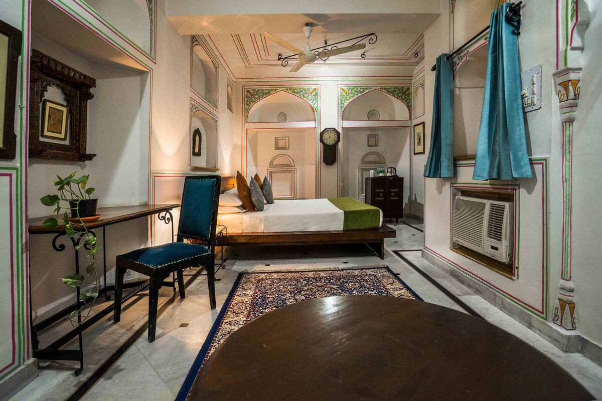Une chambre traditionnelle avec un lit, une chaise, une table et un mur décoratif.