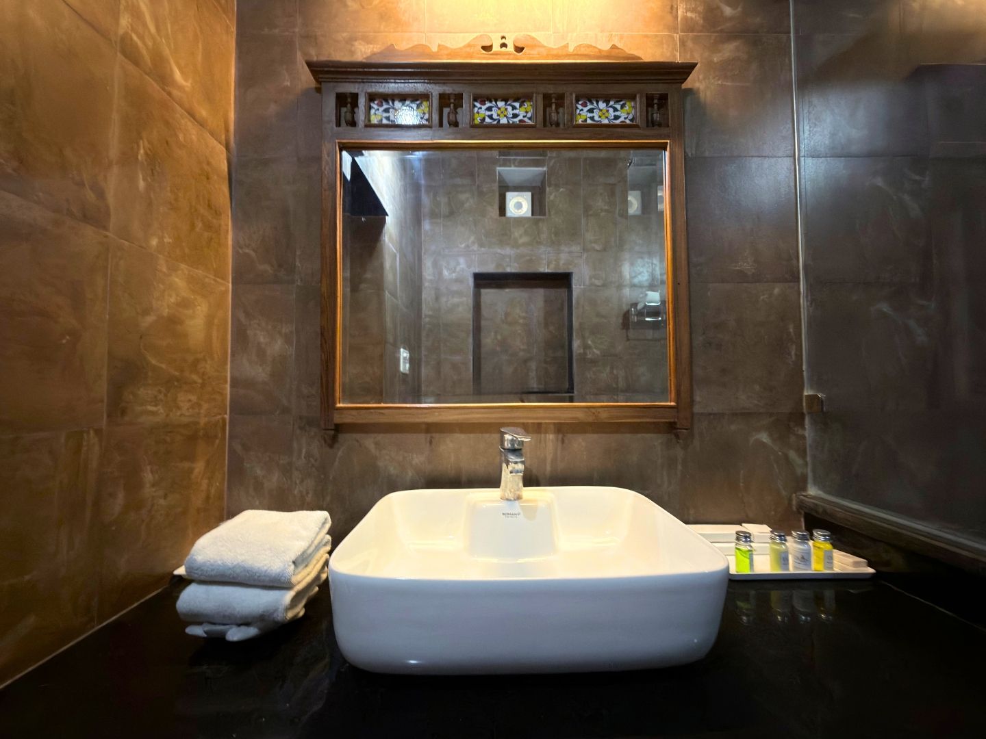 A bathroom with a large bathtub, a mirror above it, and a towel rack with folded towels.