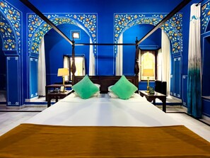 A room with a large bed, two nightstands, a window with curtains, and blue floral wall decorations. - Diggi Palace Jaipur - A City Center Hidden Heritage Gem (Jaipur)