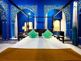 A room with a large bed, two nightstands, a window with curtains, and blue floral wall decorations.