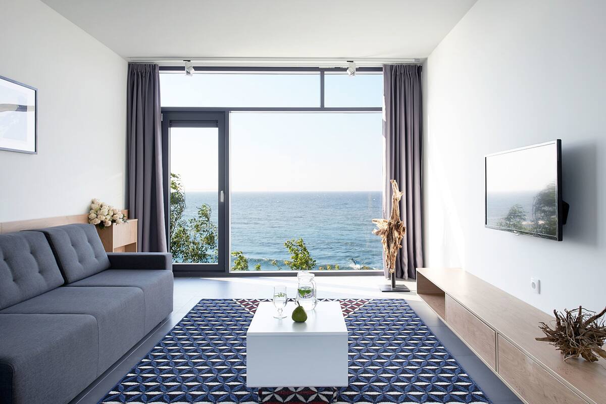 A modern living room with a grey sofa, a white coffee table, and a patterned rug.