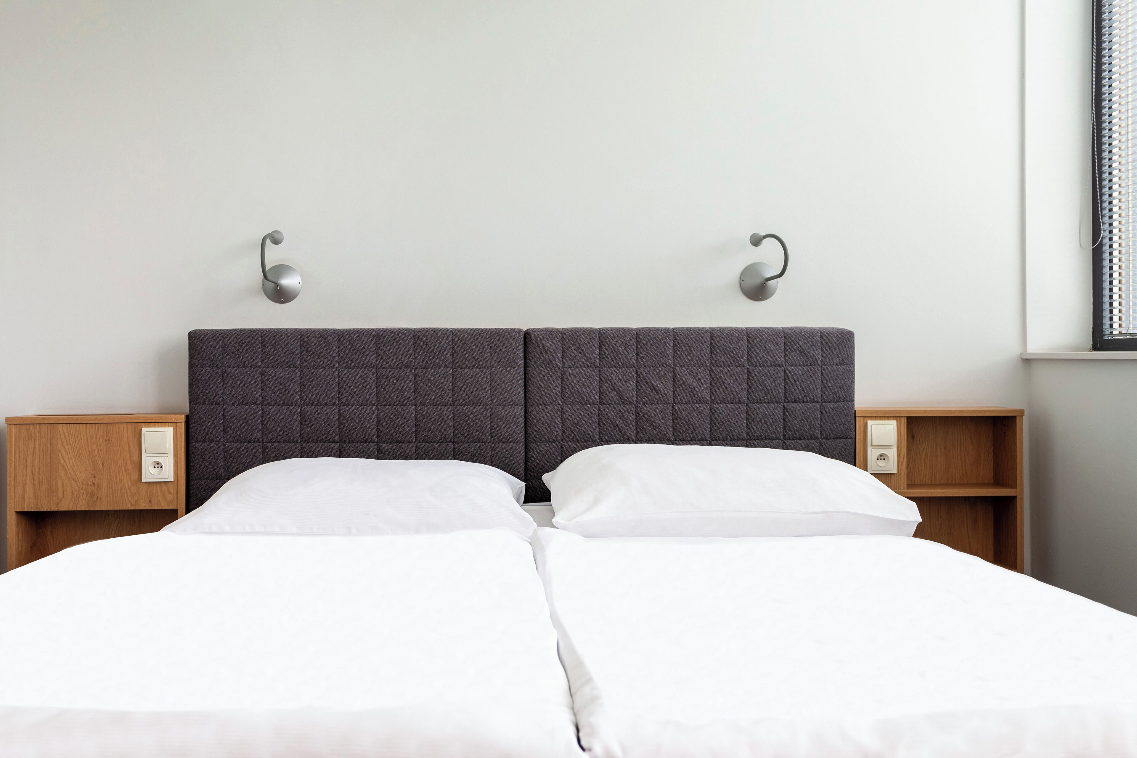 A double bed with a quilted headboard, two bedside tables, and wall-mounted nightstands.