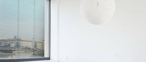 Een moderne eetruimte met een witte tafel, een grijze gestoffeerde bank en een hanglamp.