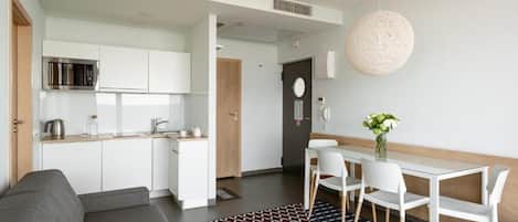Eine moderne Küche mit weißen Schränken, einer Mikrowelle und einem Essbereich mit Tisch und Stühlen.