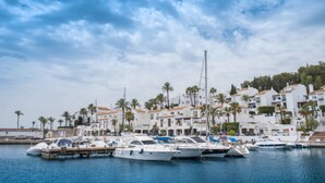 A marina with boats docked, surrounded by white buildings with orange roofs and palm trees. - H.Boutique la Caleta bay (Almunecar)