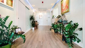 A hallway with wooden flooring, potted plants, framed artwork, and a reception desk. - H.Boutique la Caleta bay (Almunecar)