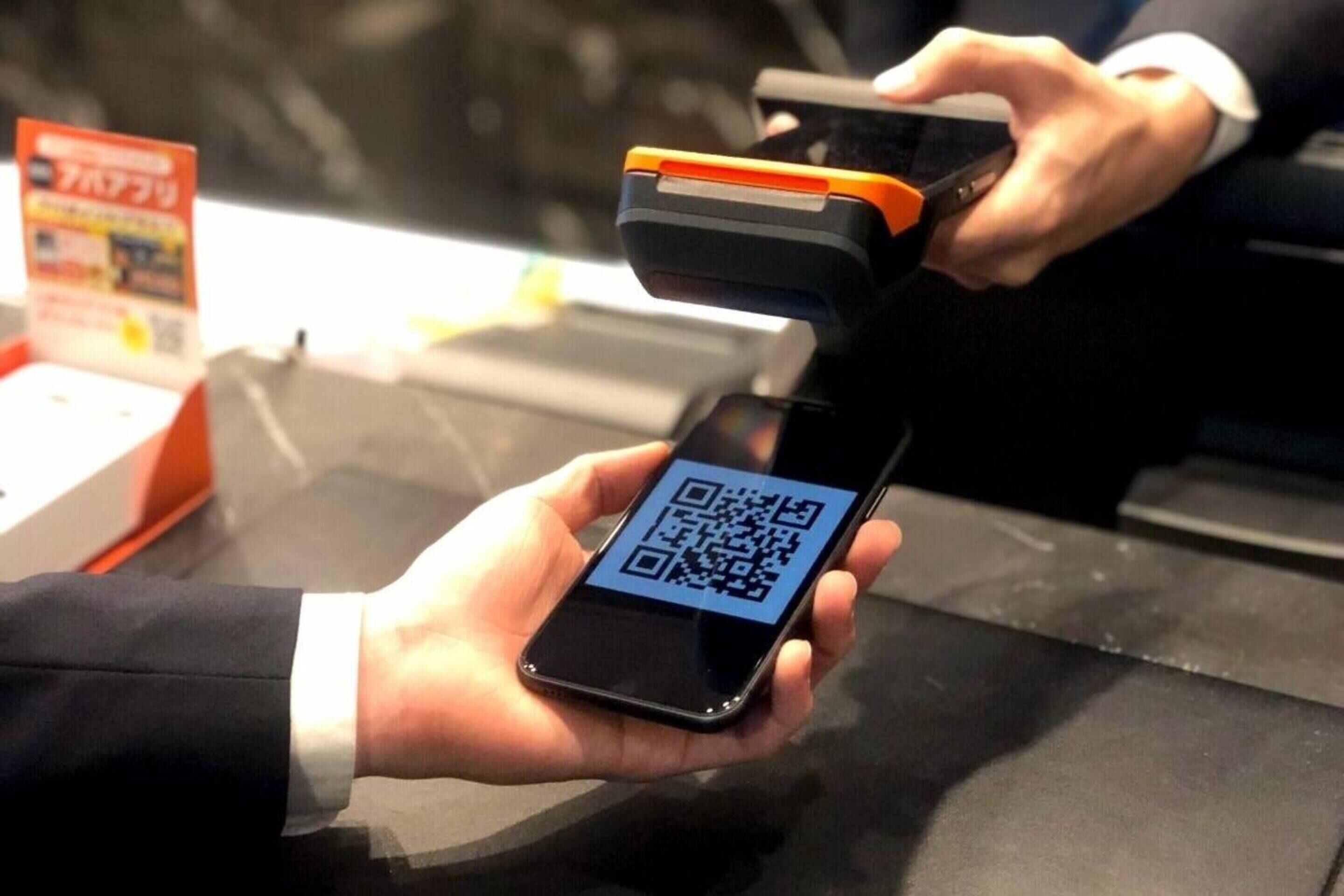 Una persona sosteniendo un teléfono inteligente con un código QR mostrado en la pantalla.