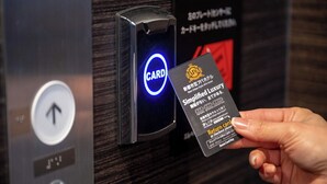 A hand holding a card near a card reader with a blue light, indicating a payment method. - APA Hotel Isesakieki Minami (Isesaki)