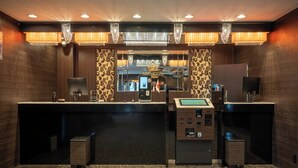 A hotel reception area with a reception desk, a cash register, a mirror, and a chandelier. - APA Hotel Isesakieki Minami (Isesaki)