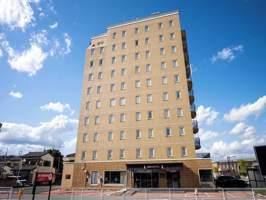 Um hotel de vários andares com fachada plana, várias janelas e entrada no térreo.