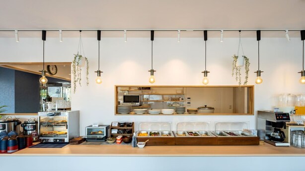 A modern breakfast bar with a variety of food containers, a coffee machine, and hanging plants. - APA Hotel Isesakieki Minami (Isesaki)