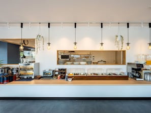 A modern breakfast bar with a variety of food containers, a coffee machine, and hanging plants. - APA Hotel Isesakieki Minami (Isesaki)