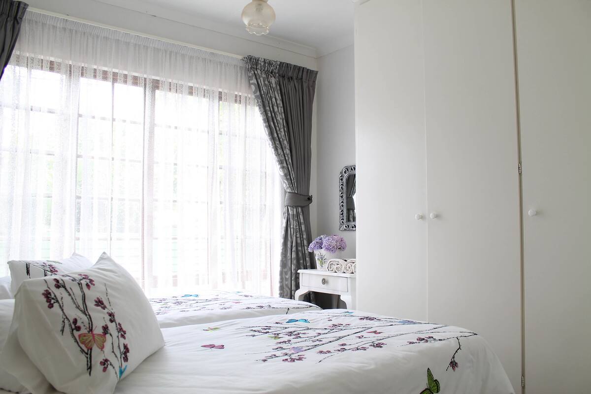 A bedroom with two beds, a dresser, and a mirror.