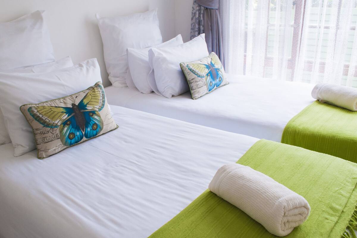 A hotel room with two beds, white bedding, and butterfly-themed pillows.