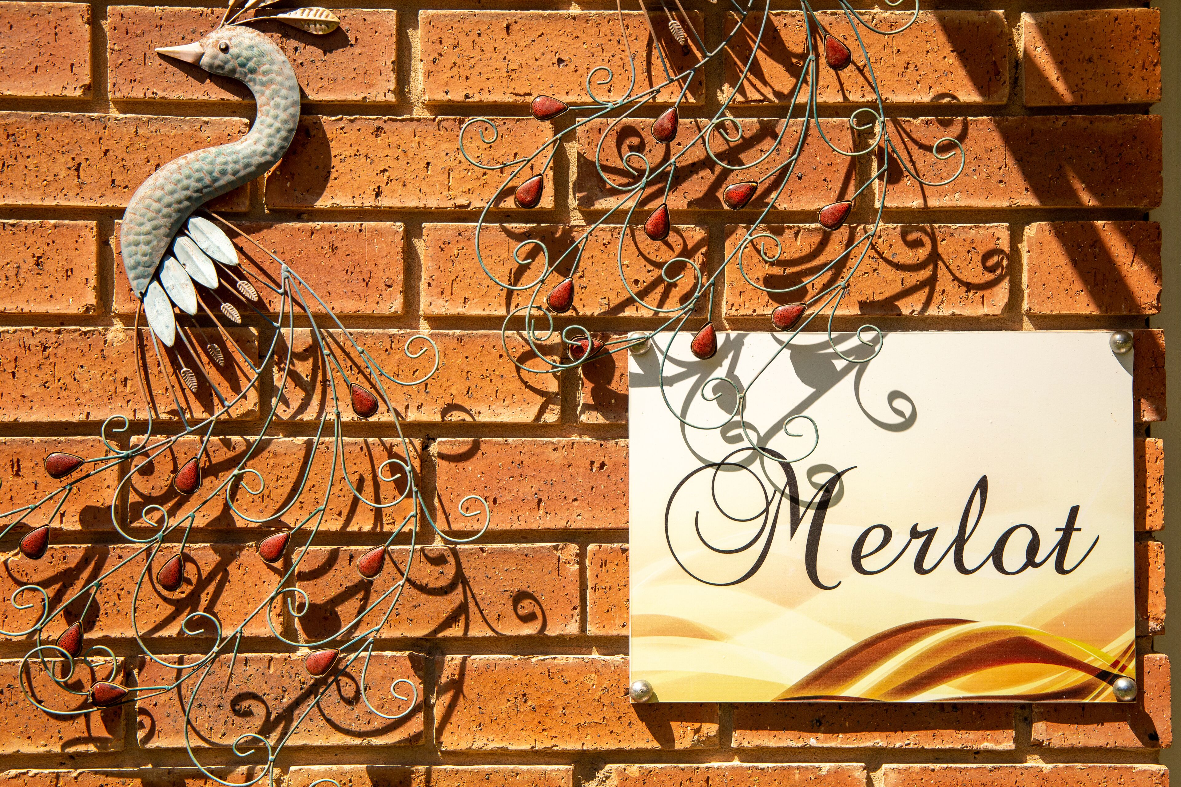 Eine Backsteinmauer mit einem verzierten Metallschwan und einem Schild mit der Aufschrift 'Merlot'.