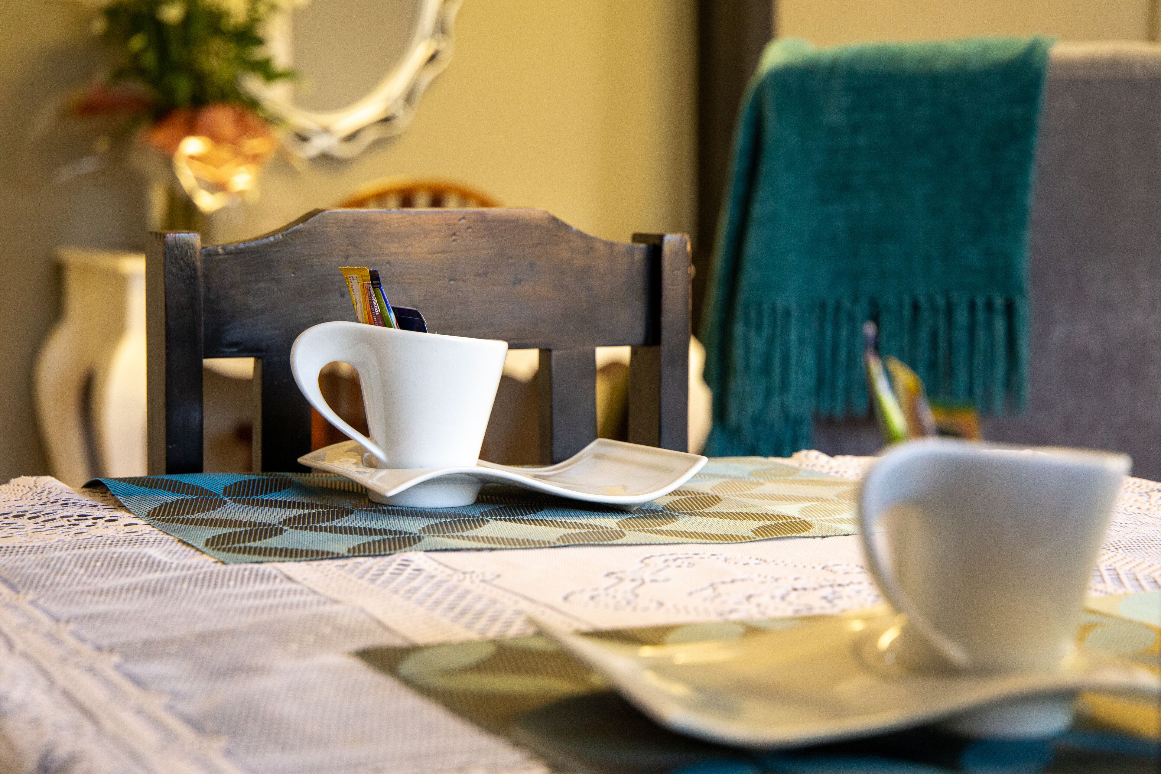 A dining table with a white cup, a white plate, and a white bowl.