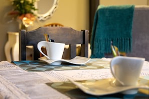 A dining table with a white cup, a white plate, and a white bowl.