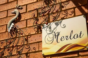 A brick wall with a decorative metal swan and a sign that reads "Merlat."