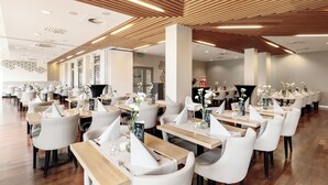 A modern restaurant with white chairs and wooden tables, featuring a wooden ceiling and a clean, minimalist design. - Diune Hotel (Kolobrzeg)