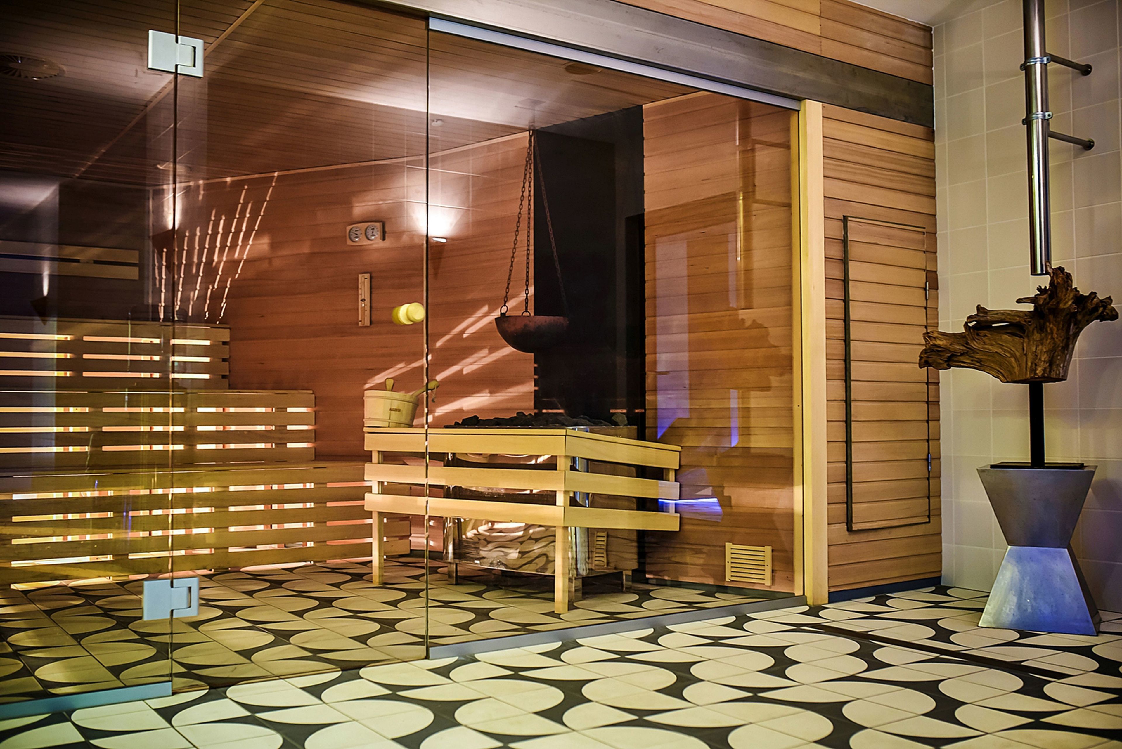 A sauna room with wooden walls, a bench, and a hanging light fixture.