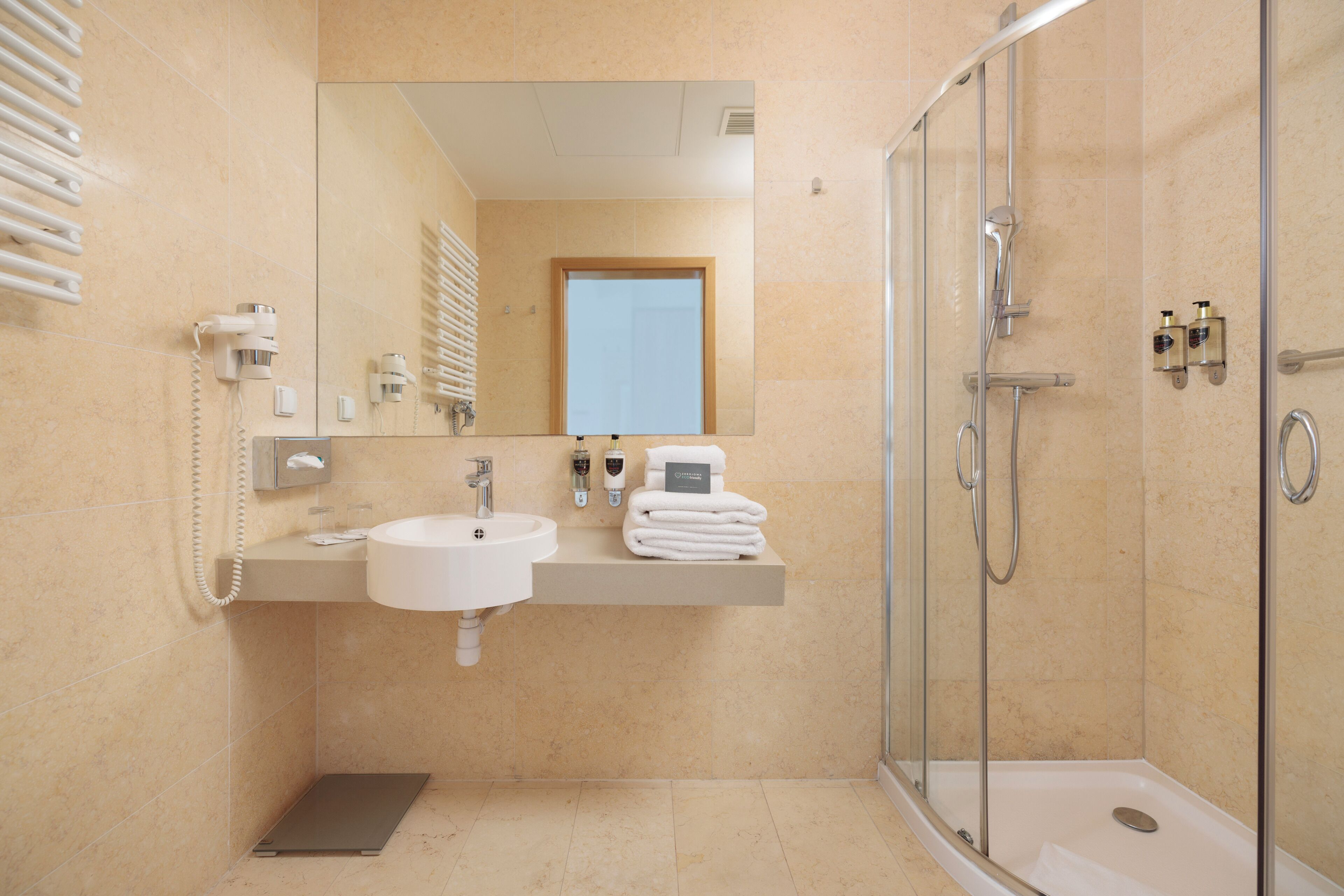 Un baño moderno con lavabo, espejo, toallero y cabina de ducha con paredes de vidrio.