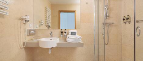 Un baño moderno con lavabo, espejo, toallero y cabina de ducha con paredes de vidrio.