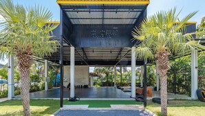Ein überdachter Außenbereich mit Betonboden, Palmen und einem Metalldach.