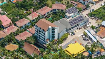 Vista aérea de una zona residencial con varias casas, un edificio grande con paneles solares y una estructura amarilla.