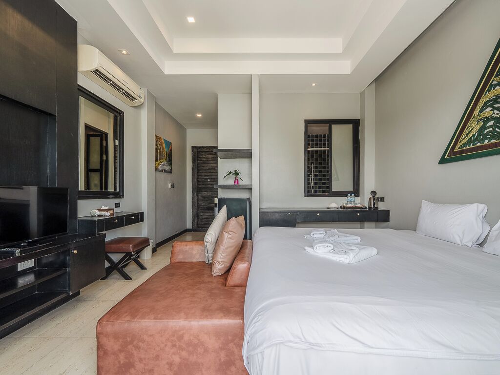 Una habitación de hotel moderna con una cama grande, un televisor de pantalla plana, un escritorio y una zona de estar.
