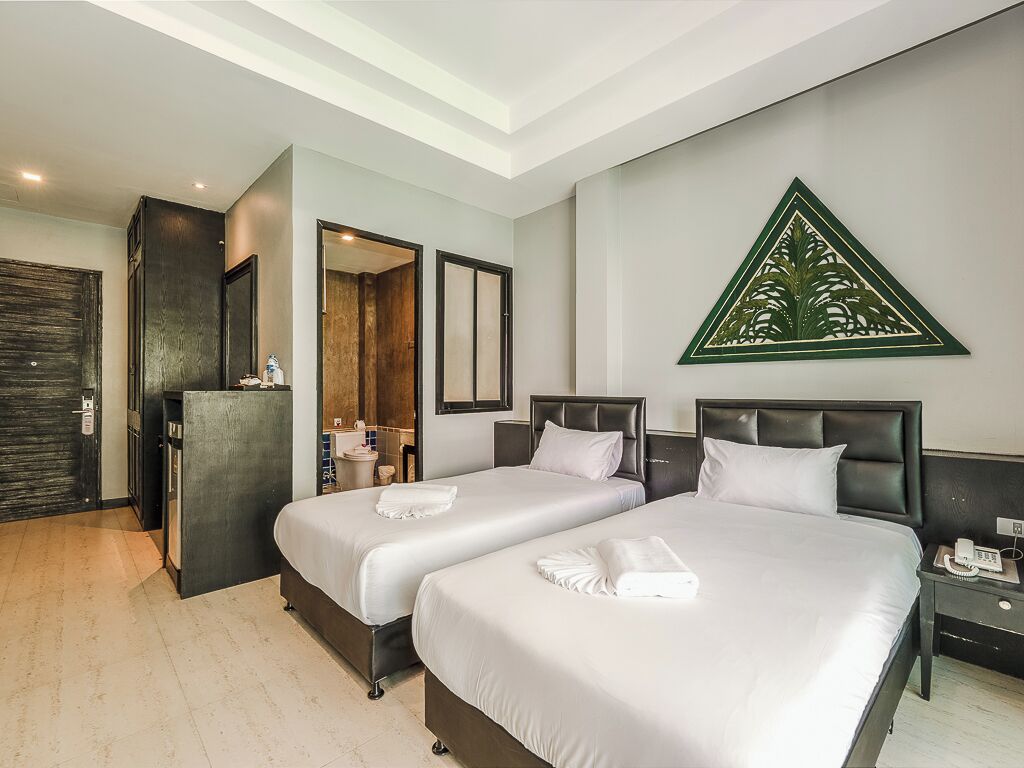 Une chambre d’hôtel avec deux lits, un bureau et un miroir.