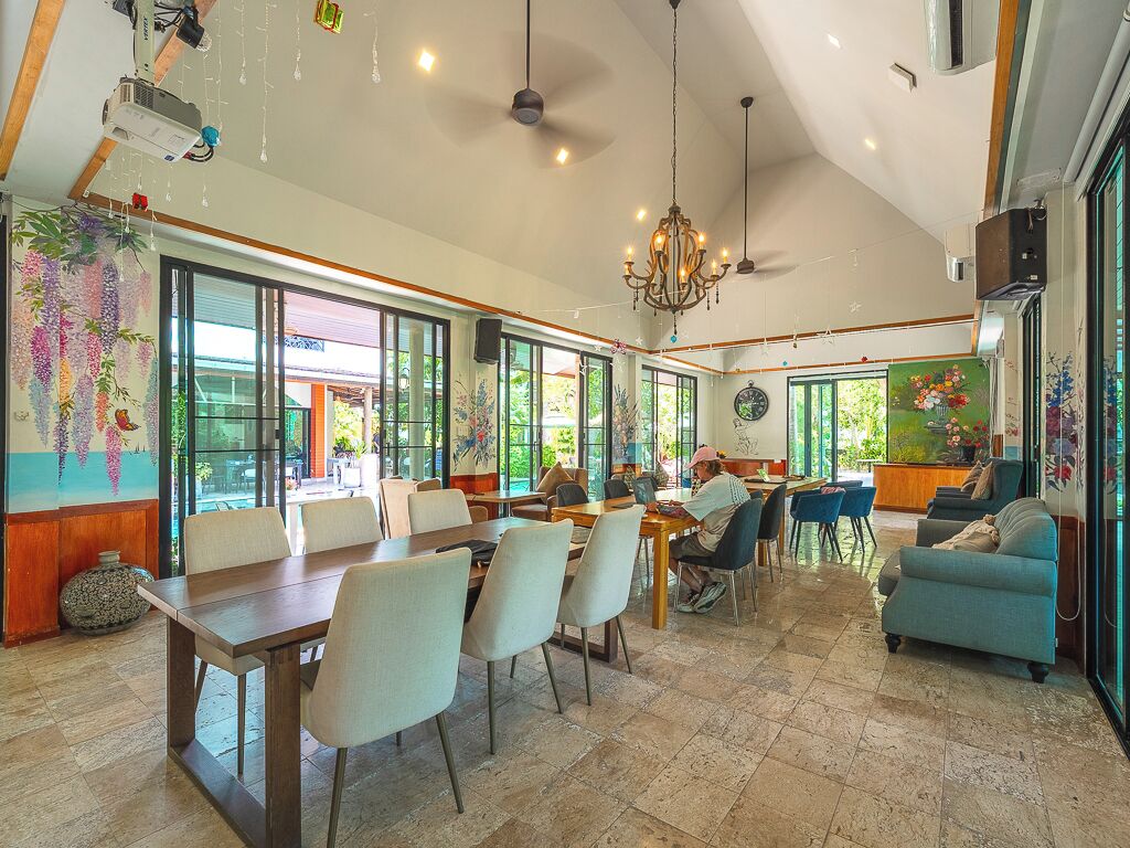 A spacious dining area with large windows, a chandelier, and a view of the outdoors.