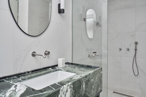 Un baño con lavamanos de mármol, espejo, inodoro y ducha.