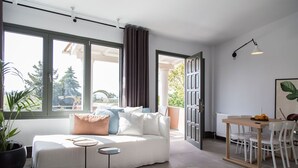 Una sala de estar moderna con un sofá, una mesita redonda y un comedor con una mesa y sillas.
