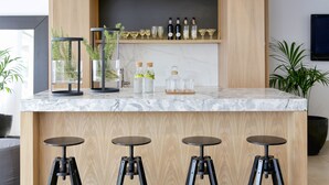 Una cocina moderna con encimera de mármol, armarios de madera y cuatro taburetes.