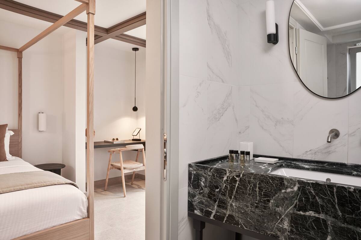 Une chambre d’hôtel moderne équipée d’un lit, d’une table de chevet et d’un bureau avec une chaise.