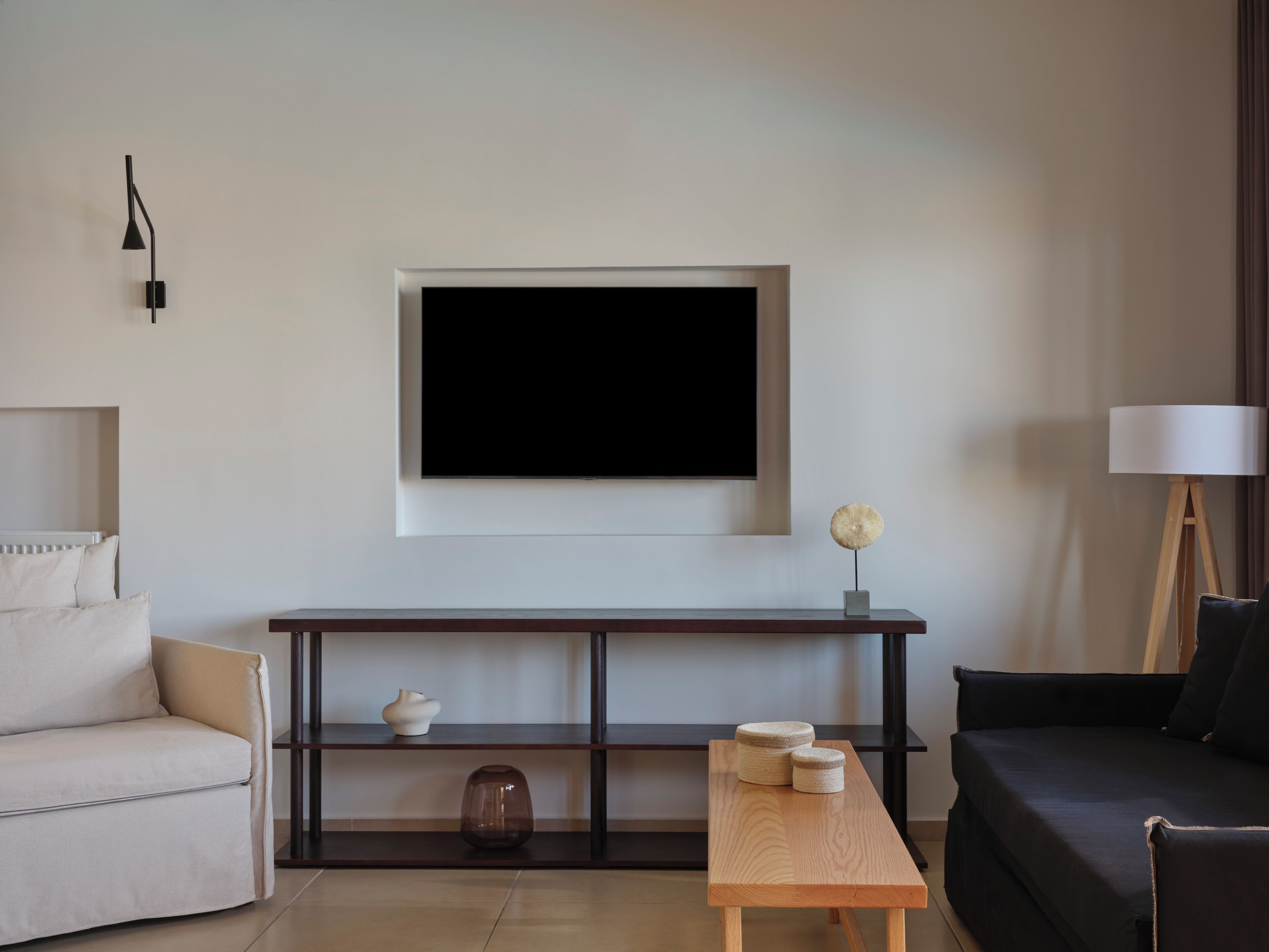 A modern living room with a sofa, a coffee table, a TV mounted on the wall, and a lamp.